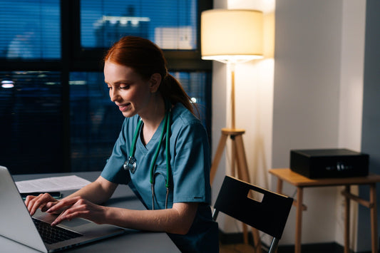 Healthcare worker in scrubs working late at a desk during a night shift