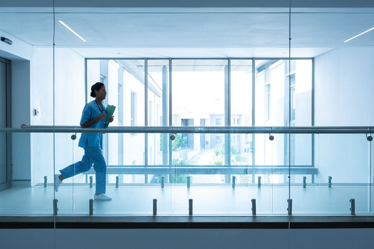 Healthcare worker in blue scrubs moving quickly down a hospital corridor